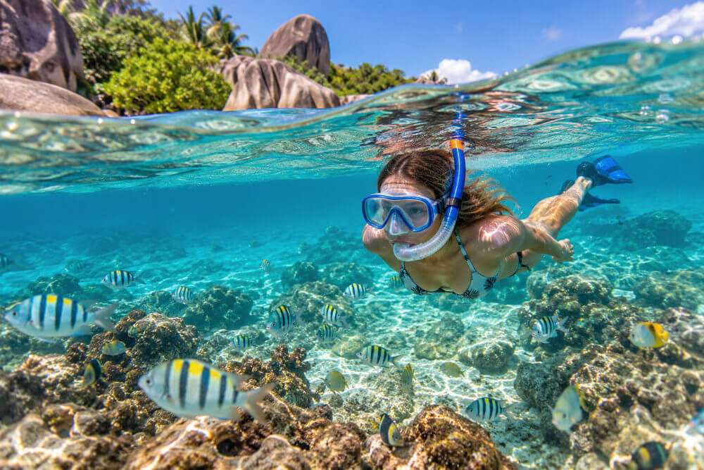 Kobieta snorkeluje nad skalistą rafą przy plaży na Seszelach